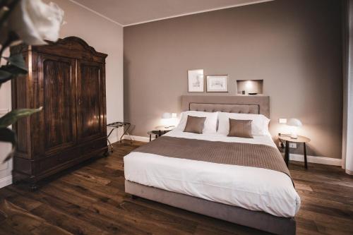 a bedroom with a large bed and a wooden cabinet at Villa Adelaide Relais & Wine in Calamandrana