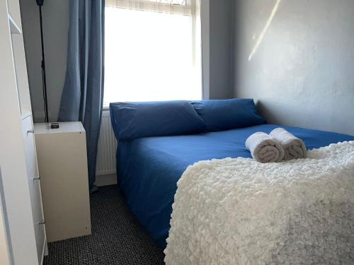 a bedroom with a blue bed with towels on it at Shirley House 4, Guest House, Fully Equipped Kitchen with Fridge, Washer, Dryer, Self Catering, Self Check in, Great for Contractors, 5 min to BAT, 20 min to Fawley Refinery, close to Southampton Central, Ideal for Longer Stays in Southampton