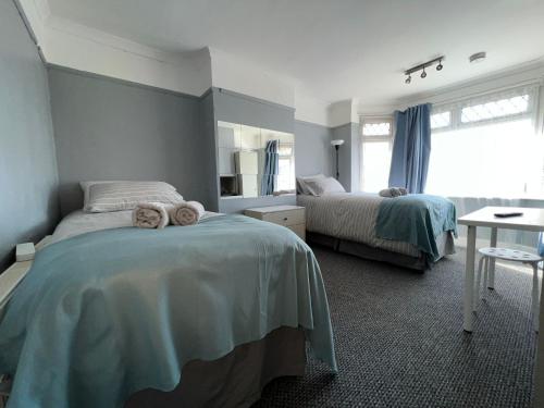 a bedroom with two beds and a table in it at Shirley House 4, Guest House, Self Catering, Self Check in with smart locks, use of Fully Equipped Kitchen, close to City Centre, Ideal for Longer Stays, Excellent Transport Links in Southampton