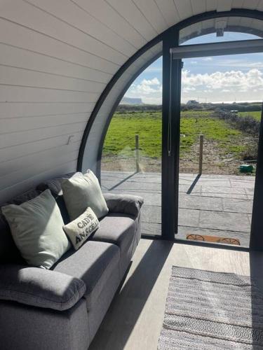 a couch sitting in a room with an open door at Gaoth na Mara pod in Doolin