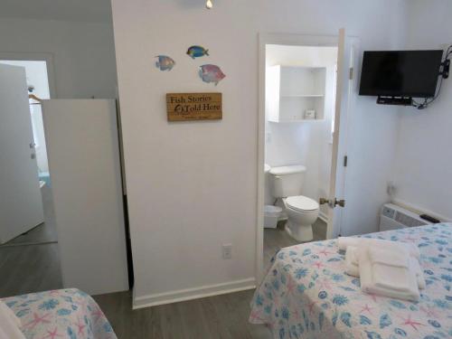 a bedroom with a bed and a bathroom with a toilet at Saltaire Cottages in Kitty Hawk Beach