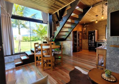 uma sala de estar com uma escada e uma mesa e cadeiras em AriMara Chalés & Ecoturismo em Praia Grande
