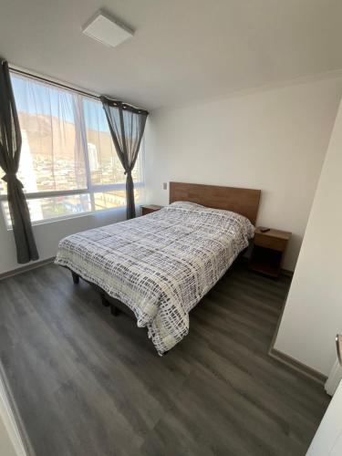 um quarto com uma cama e uma grande janela em apartamento Lynch Costero Iquique em Iquique