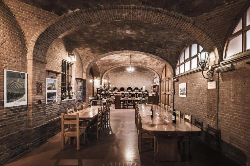a dining room with tables and chairs and a brick wall at Villa Adelaide Relais & Wine in Calamandrana