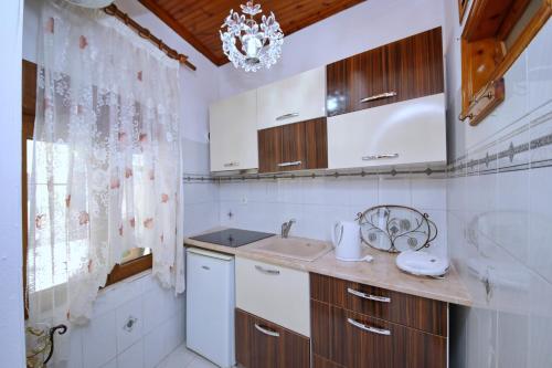 a kitchen with white cabinets and a sink and a window at Vasia's Small Villa in Skopelos Town