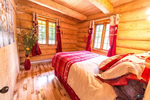 ein Schlafzimmer mit einem Bett in einem Blockhaus in der Unterkunft Chalet bois rond aux paysages uniques avec Spa ! in Lac-aux-Sables