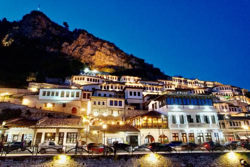 un bâtiment situé sur le côté d'une montagne la nuit dans l'établissement HOTEL ANSEL, à Berat
