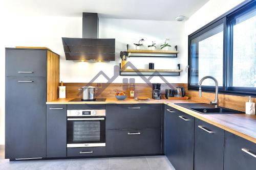 eine Küche mit dunkelblauen Schränken und einem Waschbecken in der Unterkunft LocaLise - M68 - An Aod Melen - Maison neuve à 50m de la plage et à quelques pas du centre et des plages - Draps inclus - Wifi inclus in Le Guilvinec
