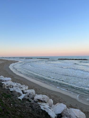 a beach with rocks and the ocean at sunset at CinziaHome Boutique B&B Spiaggia Privata in Lido di Fermo
