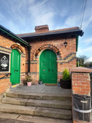 a brick building with green doors and stairs at The Railway Sleeper in Cullybackey
