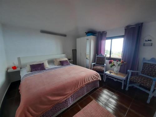 a bedroom with a bed and a chair and a window at Mi Placer in Valverde