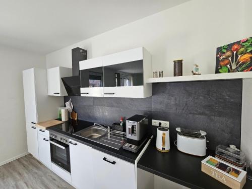 a kitchen with white cabinets and a black counter top at Ferienwohnung - Melina - in Winsen Aller