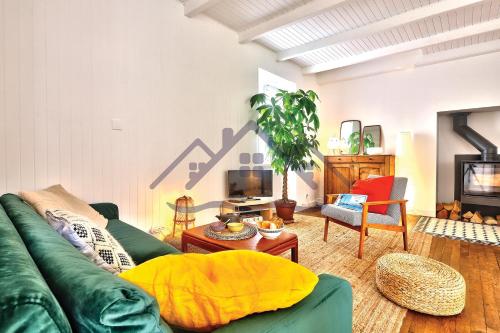 a living room with a green couch and a tv at LocaLise - M20 - La maison des Dunes à 2 pas du centre - Tout à pied, plage, port, centre, commerces marché - Wifi inclus - Linge de lit inclus - Animaux bienvenus in Le Guilvinec