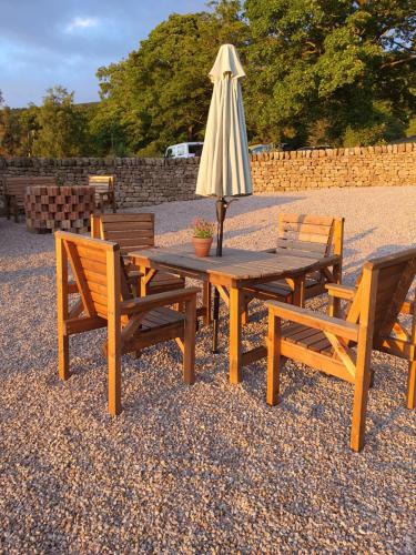 a wooden table with an umbrella and two chairs at Howgill farm Bolton Abbey in Appletreewick