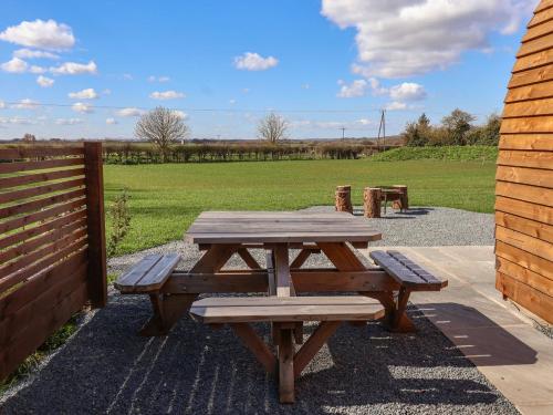 a wooden picnic table with benches next to a fence at Bevy in Harpham
