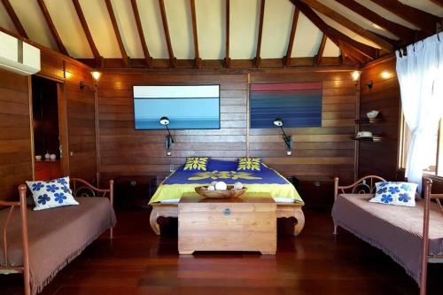 a bedroom with a bed and a tv on the wall at Villa Ylang Ylang in Haapiti