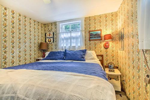 ein Schlafzimmer mit einem Bett mit blauen Kissen und einem Fenster in der Unterkunft Hartford Cottage with Dock and Private BCH on Bear Pond in Hartford