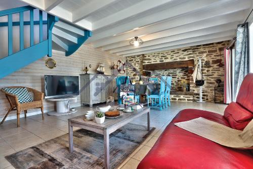 un salon avec un canapé rouge et une télévision dans l'établissement LocaLise - M3A La Maison du pêcheur au Guilvinec - Chambres vue mer - A 20m de la mer située à la pointe de Men Meur - Tout à pied, plage, port, centre, commerces, marché - Wifi inclus - Linge de lit inclus - Jardin clos - En option , ménage et serviettes, au Guilvinec