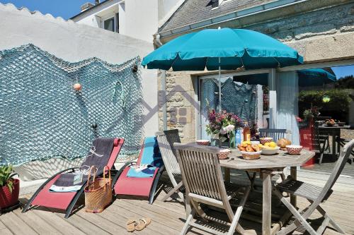 une table et des chaises avec un parasol sur une terrasse dans l'établissement LocaLise - M3A La Maison du pêcheur au Guilvinec - Chambres vue mer - A 20m de la mer située à la pointe de Men Meur - Tout à pied, plage, port, centre, commerces, marché - Wifi inclus - Linge de lit inclus - Jardin clos - En option , ménage et serviettes, au Guilvinec