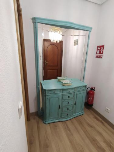 uma casa de banho com uma cómoda azul e um espelho em Apartamento de 120m2 al lado de Cabarceno em Sarón