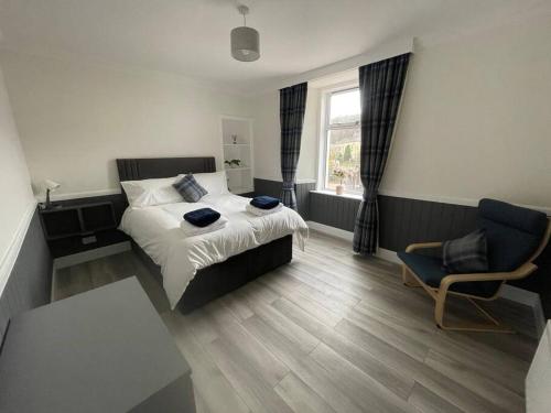 a bedroom with a bed and a chair and a window at Strathisla Garden Apartment, Oban in Oban