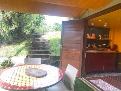 een patio met een tafel en stoelen en een keuken bij Aluna Ecolodge in Petit-Bourg