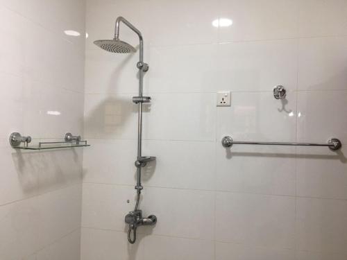 eine Dusche im Bad mit weißen Fliesen in der Unterkunft JM Apartment in Kigali