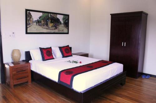 a bedroom with a large bed with a wooden cabinet at Green CoCo HomeStay in Hoi An