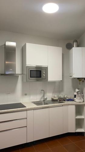 a kitchen with white cabinets and a sink and a microwave at Casa Valentina 1 in Perugia
