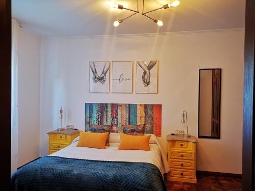 a bedroom with a bed with orange pillows and two night stands at Apartamento Alecrin Padrón in Padrón