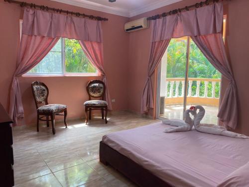 sypialnia z 2 łabędzami na łóżku i oknami w obiekcie 4 bedroom villa, security, private pool, ocean view w mieście Sosúa