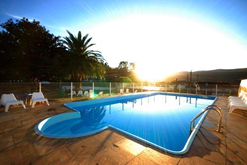 a large swimming pool with the sun in the background at Hotel París in Poio