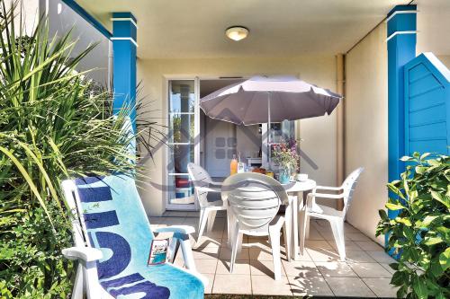 une terrasse avec une table, un parasol et des chaises dans l'établissement LocaLise au Guilvinec - B5 - Plain-pied avec piscine et jardin - Tout à pied, plage, port, centre, commerces, marché - Wifi inclus - Linge de lit inclus - Animaux bienvenus, au Guilvinec