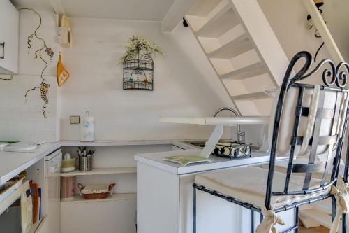 a white kitchen with a staircase and a chair at Studio With Balcony Overlooking The Port in Grimaud