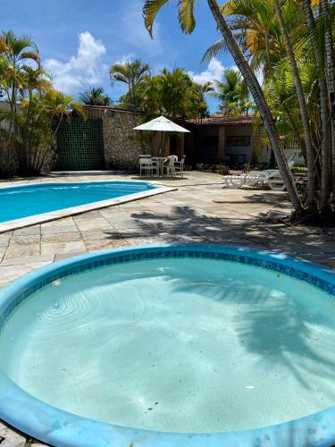 a large blue swimming pool in a yard with palm trees at Village do Sossego in São José da Coroa Grande