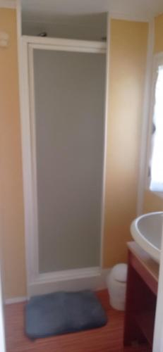 La salle de bains est pourvue d'un lavabo et d'un tapis bleu. dans l'établissement CAMPING LE BEL AIR mobil home LE FIGUIER 6 personnes, à Limogne-en-Quercy