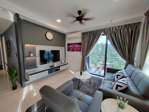 a living room with a blue couch and a tv at Ipoh Sunway Onsen Suites and Tambun Guesthouse , 3-14pax 2parking by IWH in Ipoh
