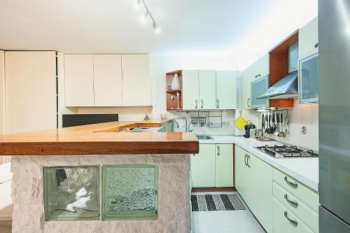a kitchen with white cabinets and a wooden counter top at Pavillon d'Angleterre au cœur de la ville in Menton