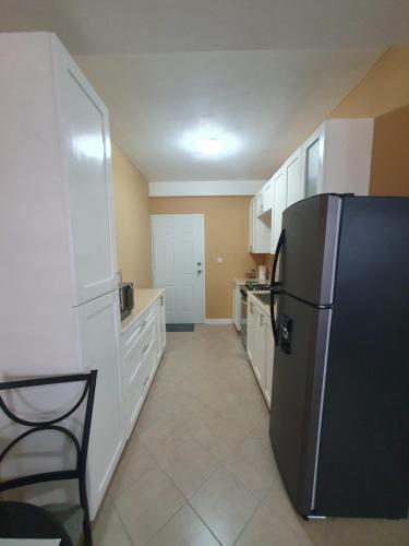 a kitchen with a black refrigerator and white cabinets at VIP Residence - Ocean & Pool view Lovely 2-Bedroom Apartment in Roseau