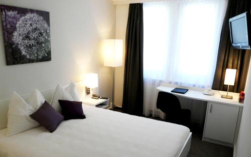 Habitación de hotel con cama blanca y escritorio en Fontana Garni, en Twann