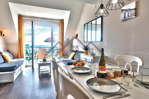 uma cozinha com uma mesa e uma garrafa de vinho em LocaLise au Guilvinec - A22 - Belle vue sur la mer, la piscine et le jardin - Tout à pied, plages, port, centre, commerces, marché - Wifi inclus - Animaux bienvenus - Linge de lit inclus em Le Guilvinec
