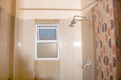 a bathroom with a shower with a window at A Cozy 3 Bed Apartment With a Swimming Pool in Nyali - Beach Front in Mombasa