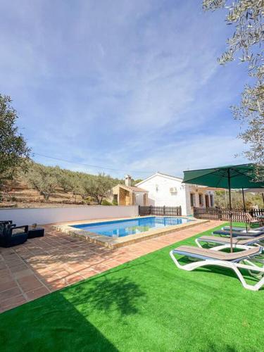 einen Pool mit zwei Liegestühlen und einem Sonnenschirm in der Unterkunft Casa rural Río Grande, Coín in Coín