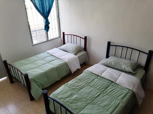 twee bedden in een kamer met een raam bij Casa D vacaciones/negocios/WiFi/CableTV/2Estaciona in Tuxtla Gutiérrez