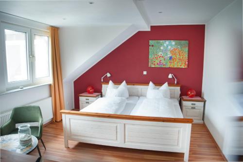 a bedroom with a large white bed with a red wall at Pension & Seminarhaus "Haus am Fluss" in Laurenburg
