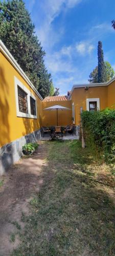 una casa amarilla con una mesa delante en Mono ambiente Loria en Luján de Cuyo