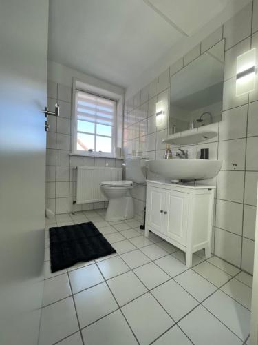 a white bathroom with a sink and a toilet at Ferienwohnung Am Bündheimer Schloss in Bad Harzburg