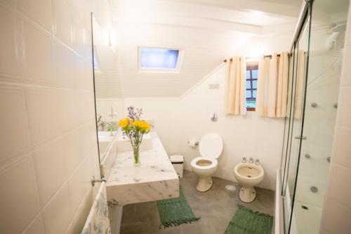 a white bathroom with a toilet and a sink at Casa das Pedras in Monte Verde