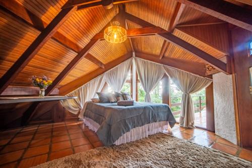 ein Schlafzimmer mit einem Bett in einem Zimmer mit Holzdecken in der Unterkunft Casa das Pedras in Monte Verde