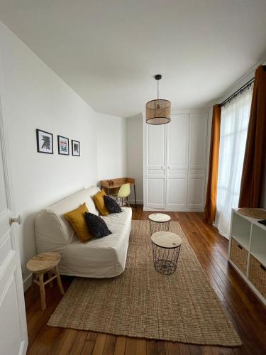 sala de estar con sofá blanco y suelo de madera en Charmant studio proche RER B direction Paris, en Fontenay-aux-Roses
